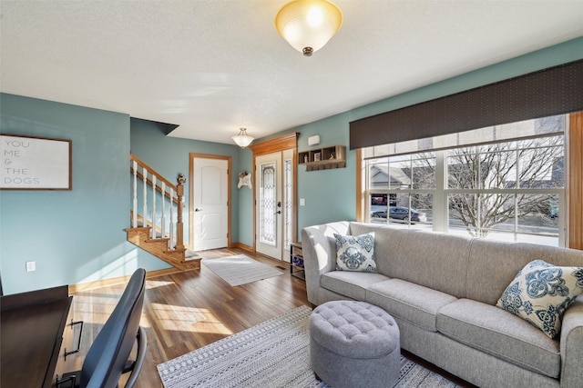 living area with baseboards, wood finished floors, and stairs