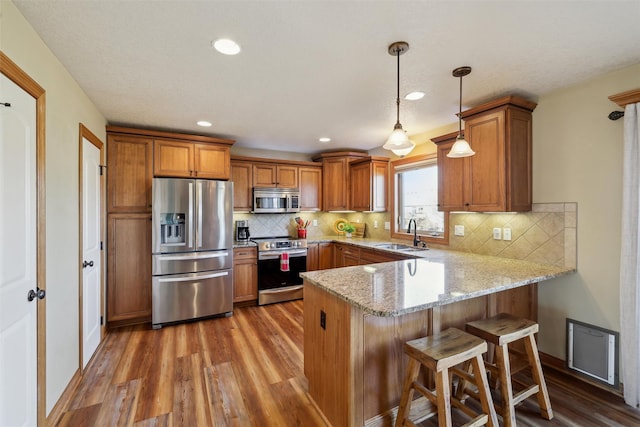 kitchen featuring a peninsula, brown cabinetry, and stainless steel appliances