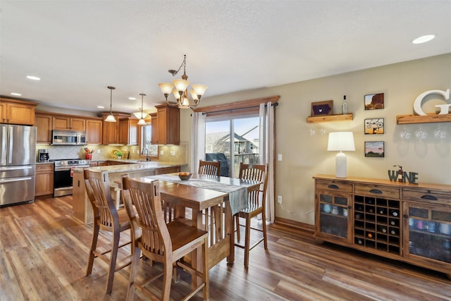 dining space with recessed lighting, baseboards, an inviting chandelier, and wood finished floors