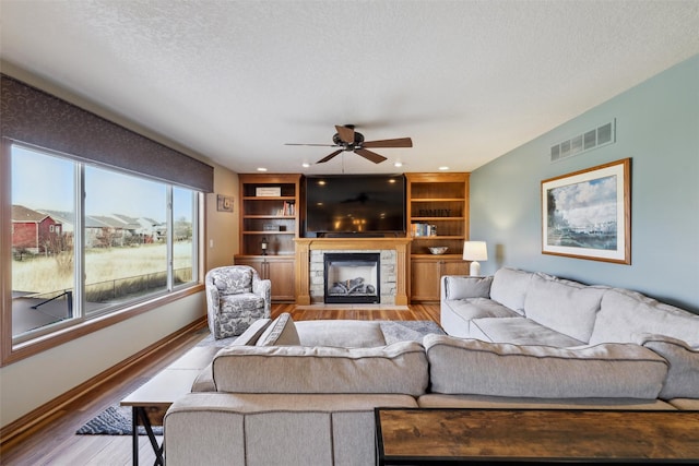 living room with a fireplace, wood finished floors, visible vents, and a textured ceiling