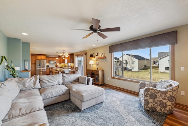 living room with recessed lighting, a textured ceiling, baseboards, and wood finished floors