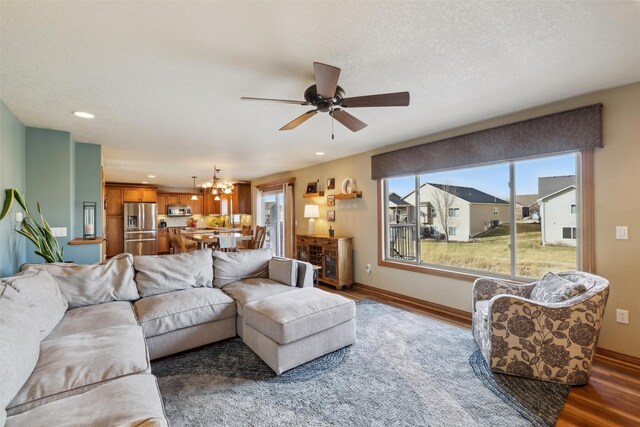 living room with recessed lighting, baseboards, wood finished floors, and ceiling fan with notable chandelier