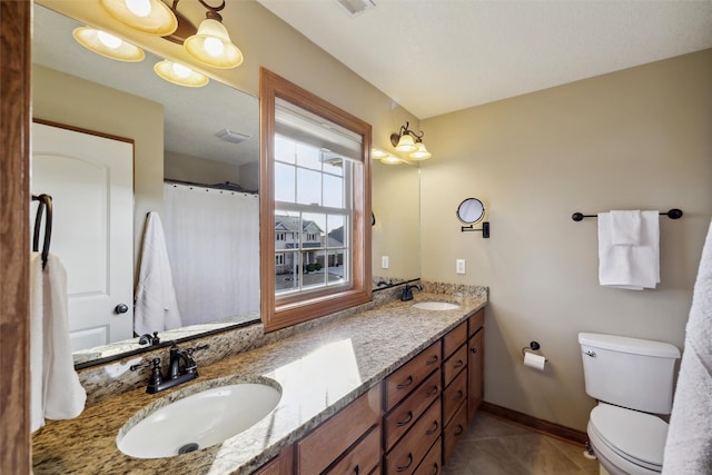 bathroom with tile patterned flooring, double vanity, toilet, and a sink