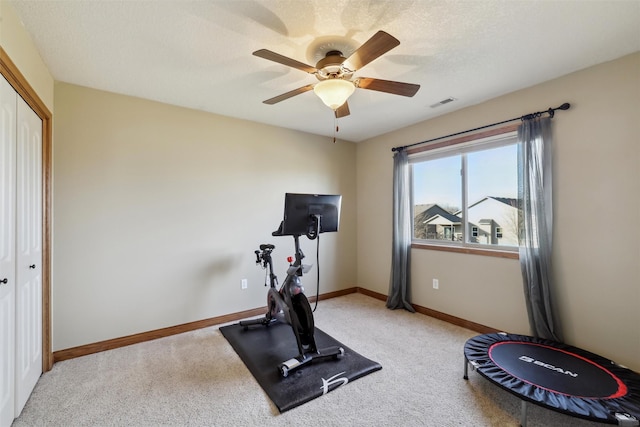 exercise room featuring carpet flooring, baseboards, visible vents, and a textured ceiling