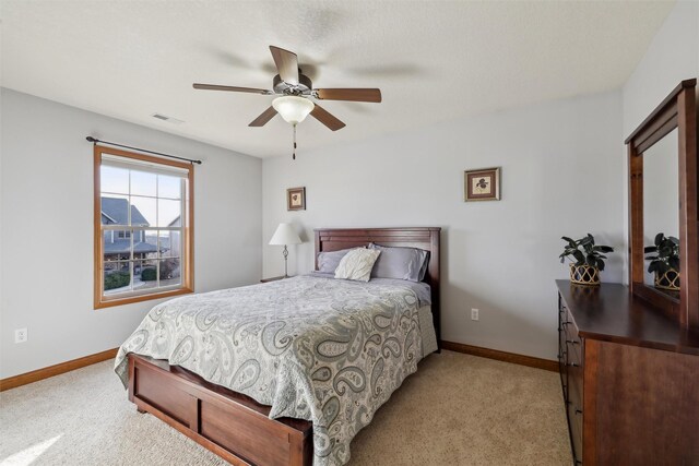 bedroom with visible vents, light carpet, baseboards, and ceiling fan