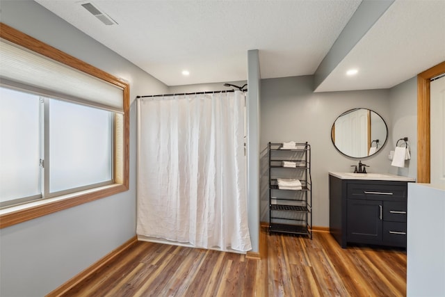 bathroom featuring visible vents, vanity, baseboards, and wood finished floors