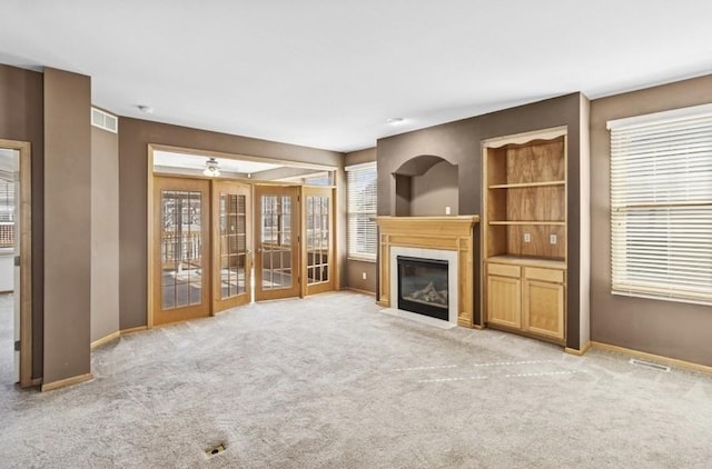 unfurnished living room featuring baseboards, visible vents, a fireplace with flush hearth, and light carpet