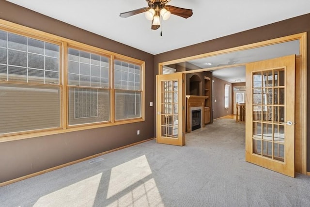 unfurnished living room with visible vents, ceiling fan, carpet flooring, french doors, and a fireplace