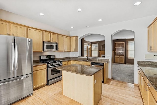 kitchen with a kitchen island, recessed lighting, dark stone countertops, appliances with stainless steel finishes, and light wood-style flooring