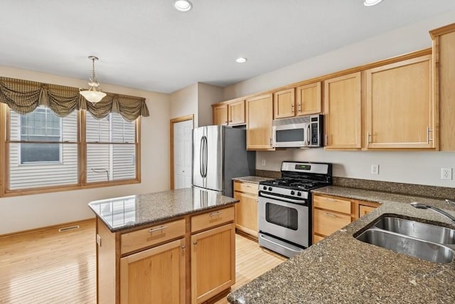 kitchen featuring light brown cabinetry, light wood-style flooring, appliances with stainless steel finishes, and a sink