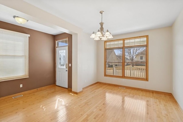 interior space with a chandelier, baseboards, visible vents, and light wood-style flooring