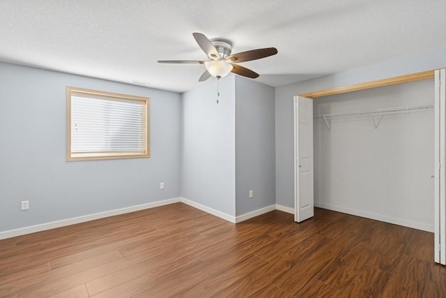 unfurnished bedroom featuring a closet, baseboards, a textured ceiling, and wood finished floors