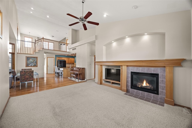 carpeted living area with recessed lighting, a tile fireplace, high vaulted ceiling, and a ceiling fan