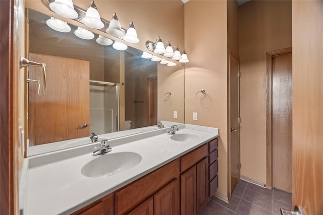 full bath with tile patterned flooring, double vanity, a shower with shower door, and a sink