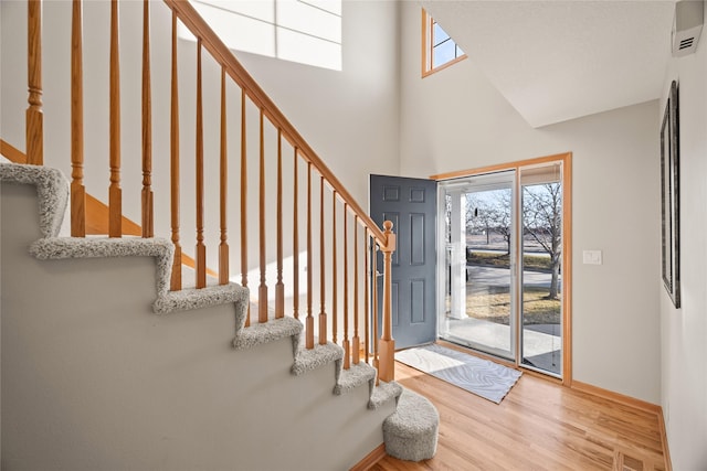 entryway with stairway, a high ceiling, baseboards, and wood finished floors