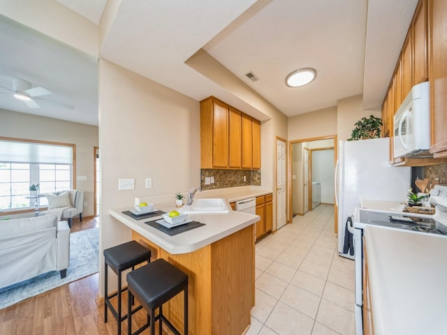 1904 NW Ashton Ln Unit 3, Ankeny, IA 50023 - kitchen with white microwave, stove, a peninsula, backsplash, and a breakfast bar area