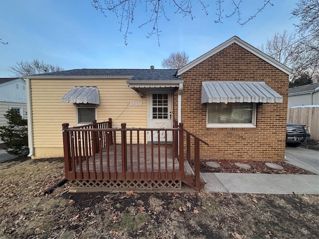 rear view of house with brick siding and roof with shingles