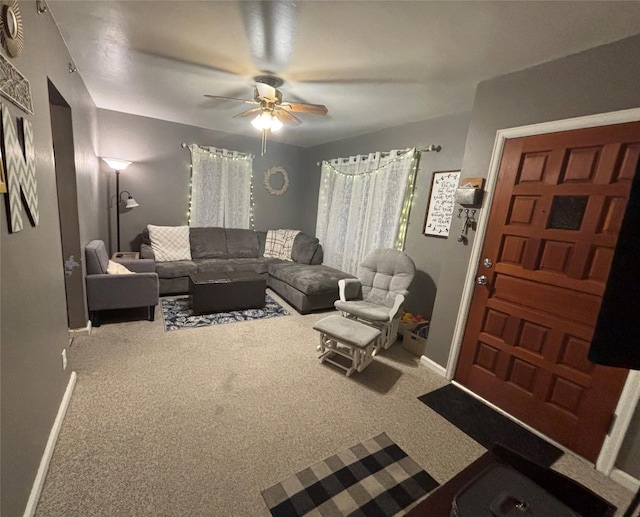 carpeted living area with baseboards and a ceiling fan