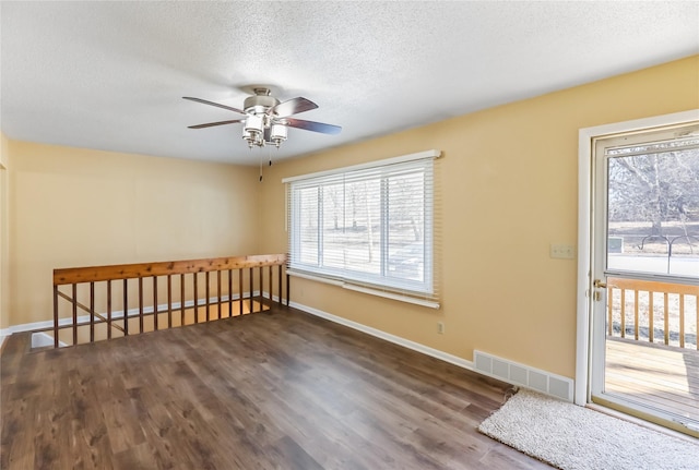 spare room featuring visible vents, a textured ceiling, baseboards, ceiling fan, and dark wood-style flooring