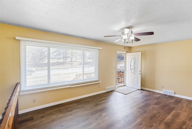 entrance foyer featuring a textured ceiling, wood finished floors, visible vents, and baseboards