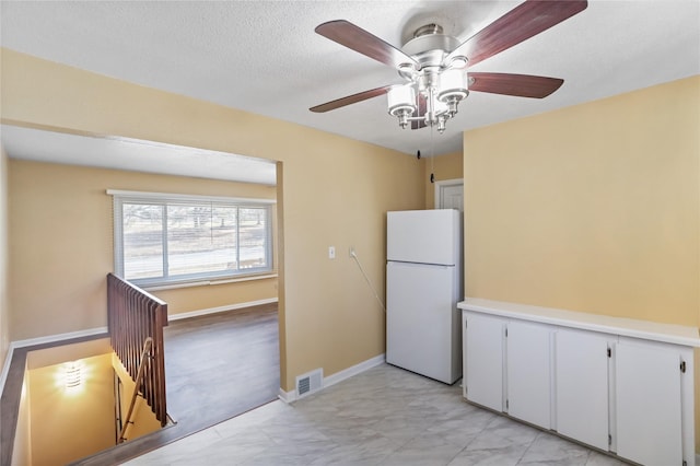 kitchen with visible vents, baseboards, freestanding refrigerator, marble finish floor, and a textured ceiling