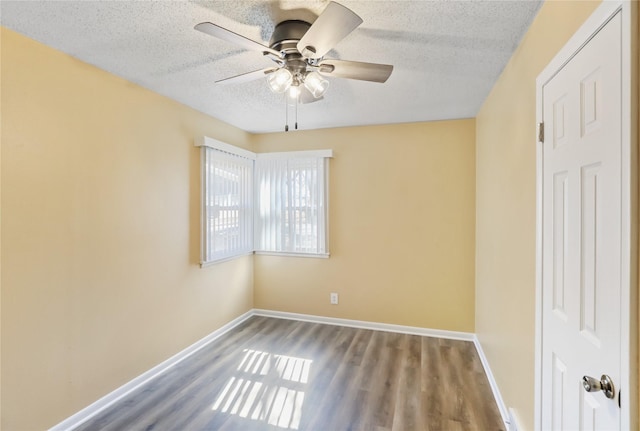 empty room featuring a ceiling fan, wood finished floors, baseboards, and a textured ceiling