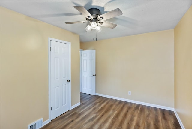 spare room featuring visible vents, baseboards, wood finished floors, and a ceiling fan