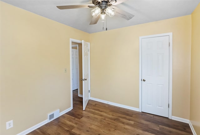 empty room with ceiling fan, visible vents, baseboards, and wood finished floors