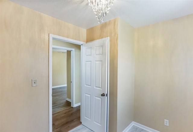 unfurnished room featuring baseboards, an inviting chandelier, and wood finished floors