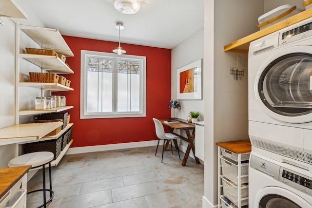 laundry area with laundry area, stacked washer / dryer, and baseboards