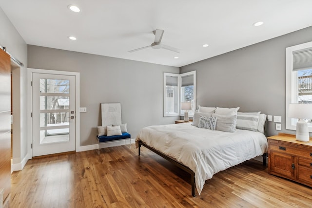 bedroom featuring a barn door, light wood-style flooring, recessed lighting, and baseboards