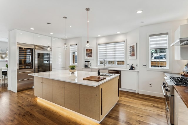 kitchen with light wood finished floors, a spacious island, recessed lighting, stainless steel stove, and modern cabinets