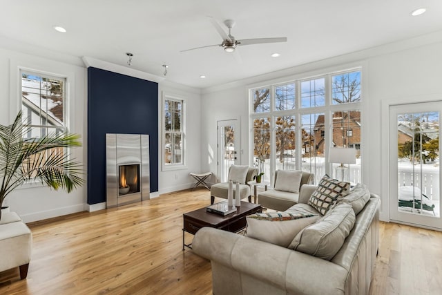 living room with plenty of natural light, light wood-style flooring, a fireplace, and baseboards