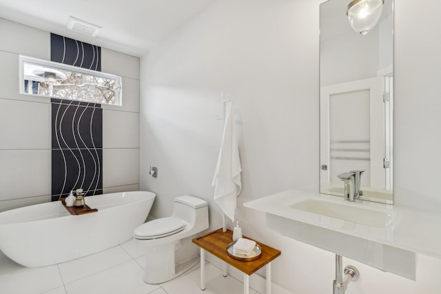 full bath featuring tile patterned floors, a freestanding tub, toilet, and a sink