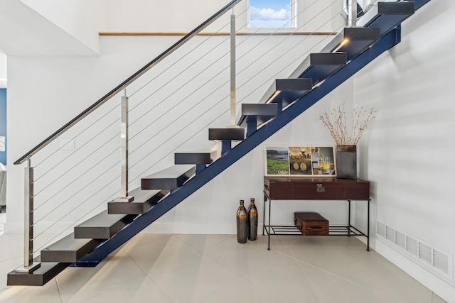 staircase featuring tile patterned flooring, visible vents, and baseboards