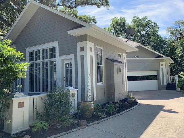 view of property exterior featuring concrete driveway and an attached garage