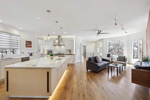 kitchen featuring a sink, wall chimney range hood, dishwasher, white cabinetry, and modern cabinets