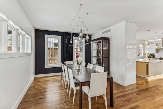 dining area featuring light wood finished floors, visible vents, baseboards, recessed lighting, and a notable chandelier