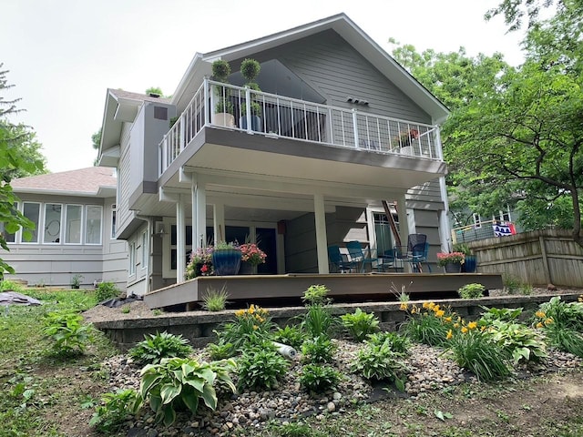 rear view of house with a balcony and fence