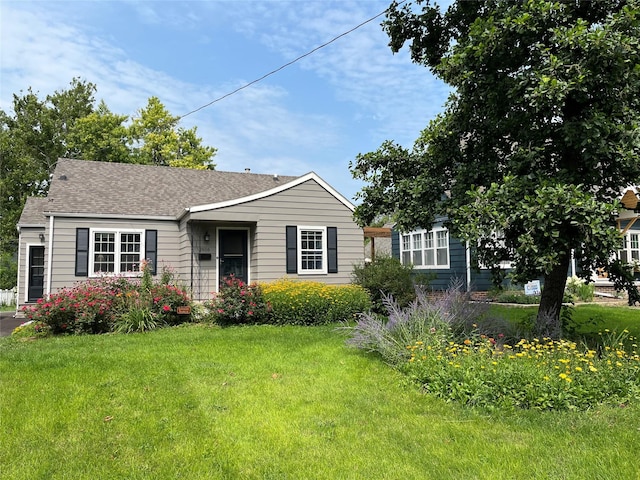 view of front of home with a front yard and a shingled roof