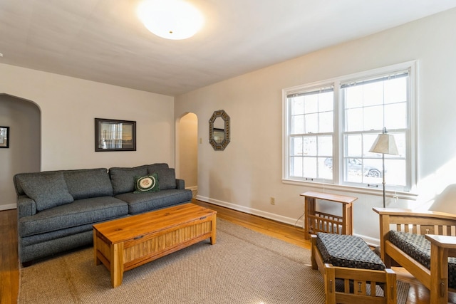 living room with wood finished floors, arched walkways, and baseboards