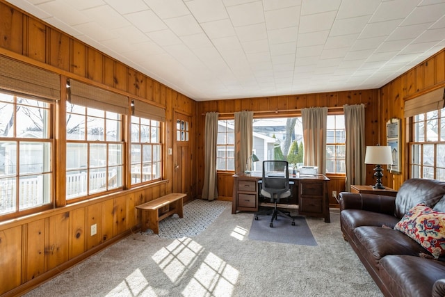 home office with light colored carpet and wood walls