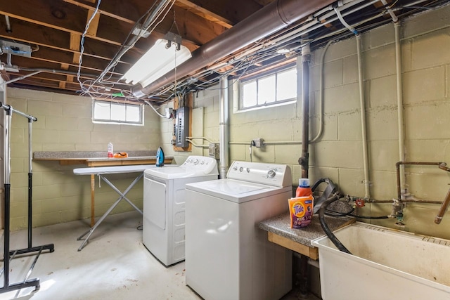 clothes washing area with washer and clothes dryer, laundry area, electric panel, and a sink