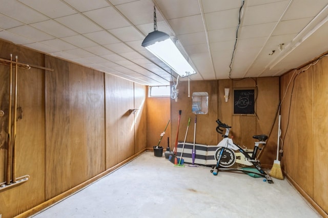 workout room featuring a drop ceiling and wood walls