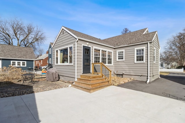 rear view of property featuring a patio and a shingled roof