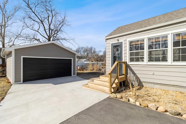 exterior space featuring a detached garage and roof with shingles