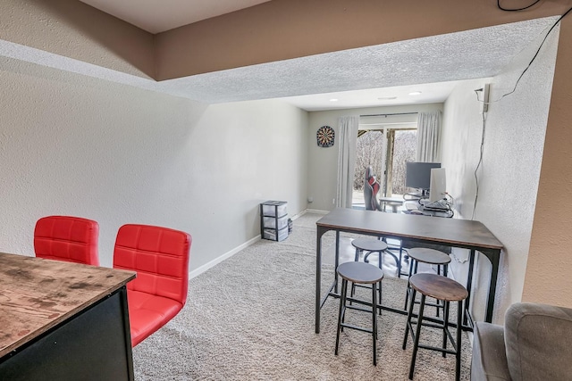 dining space with baseboards, a textured ceiling, carpet flooring, and a textured wall