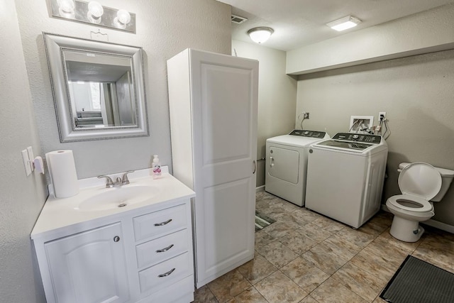 bathroom featuring vanity, visible vents, washer and dryer, toilet, and a textured wall