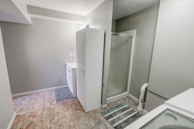 full bathroom with baseboards, a stall shower, vanity, and a textured wall