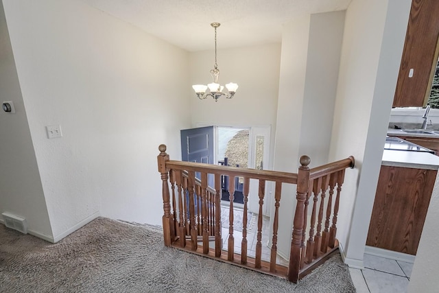 stairs with an inviting chandelier, carpet, and visible vents